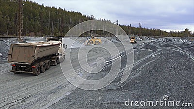 A large powerful machines working near piles of rubble. Stock. Dump truck and tractors near giant piles of crahed stones Stock Photo