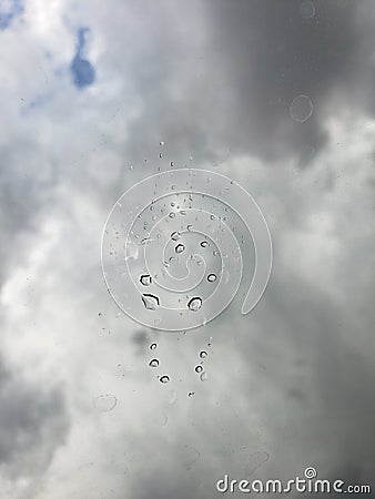 Large rain drop splattered on window looking up at a clouded sky Stock Photo