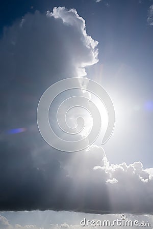 Large rainy cumulus cloud against the bright sun and sky. Abstract background. Stock Photo