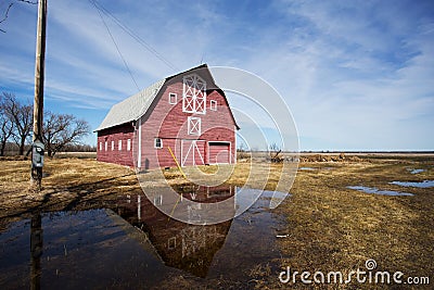 Large red barn reflected in puddle of water Stock Photo
