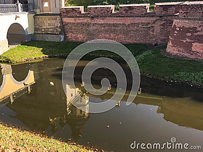 A large red brick earthen wall is strong protective and a moat with the war of an old, ancient medieval castle Stock Photo