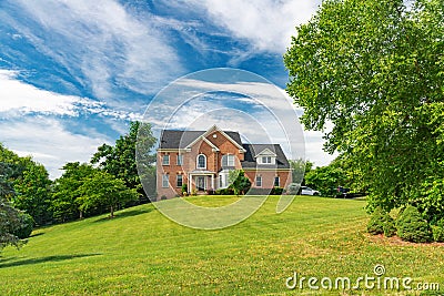 Large Red Brick Traditional Colonial Home House on a large Wooded lot. Green lawn and blue sky Editorial Stock Photo