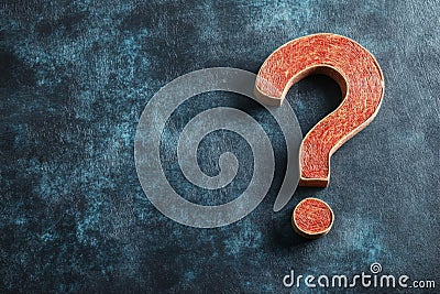 ?Large red question mark placed on a dark textured background representing questioning, inquiry, and uncertainty Stock Photo