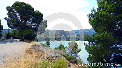 Large reservoir lake in the mountains, very blue water, pine trees on the shore, an island in distance Stock Photo