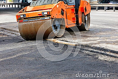 A large road vibratory roller rolls off the highway to lay fresh asphalt on the new road Stock Photo