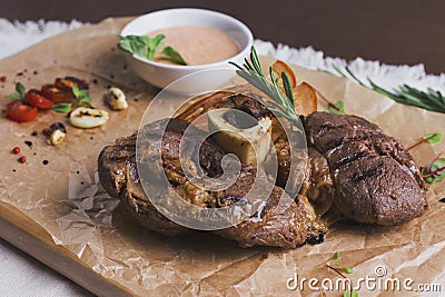 The large roasted piece of meat on bone with sauce and spices Stock Photo