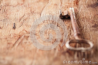 Large rusty vintage metal key on old wooden background Stock Photo