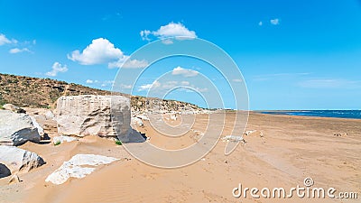 Large sandy beach with stone boulders. Summer travel Stock Photo