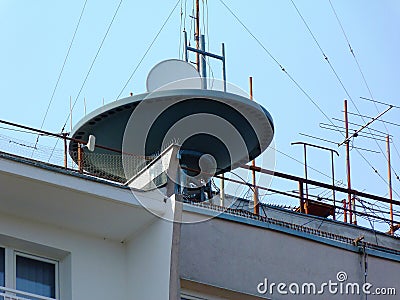 Large satellite dish receiver on flat roof of tall condo building Stock Photo
