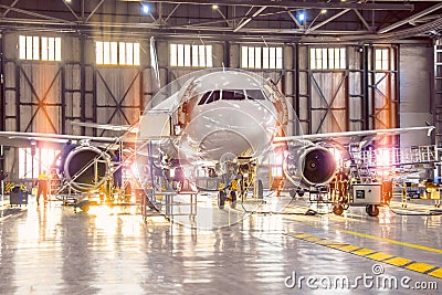 Large-scale inspection of all aircraft systems in the aircraft hangar by worker mechanics and other specialists. Bright light Editorial Stock Photo