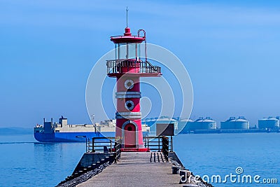 Large ship behind red lighthouse at end of pier Editorial Stock Photo