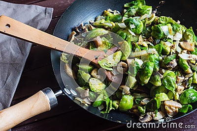 Large skillet with delicious looking sauteed brussels sprouts and mushrooms, wood turner Stock Photo