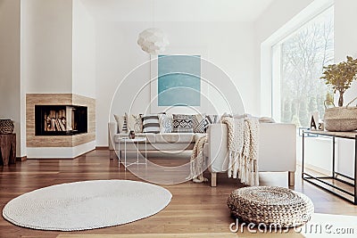 Large sky blue abstract art poster and a modern fireplace in a bright living room interior with dark hardwood floor Stock Photo