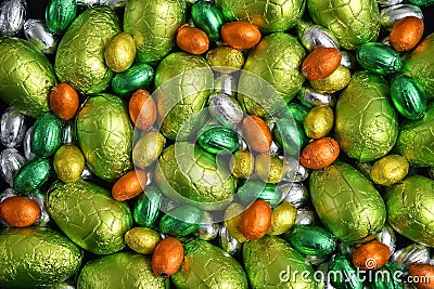 Large & small yellow, gold, orange, green and silver spring colours of foil wrapped chocolate easter eggs. Stock Photo