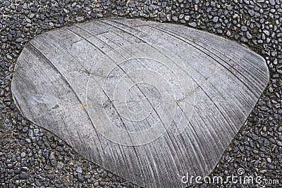 Smooth gray stone with lines on a gravel pavement and dirt Stock Photo