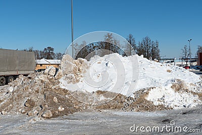 A large snowdrift in the parking lot. The truck in the parking lot got stuck in the snow. Cleaning roads from snow Stock Photo