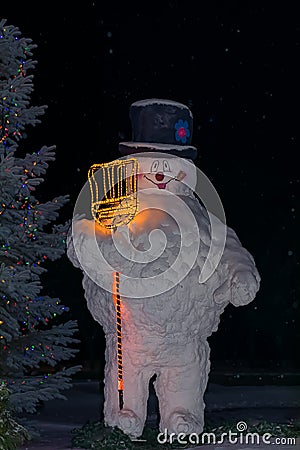 Snowman beside a Christmas tree at night. Full Snowman. Stock Photo