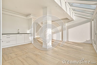 A large spacious room with a small kitchen and a staircase Stock Photo