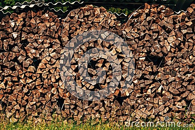 Large stack of chopped firewood on farmland drying in summer Stock Photo