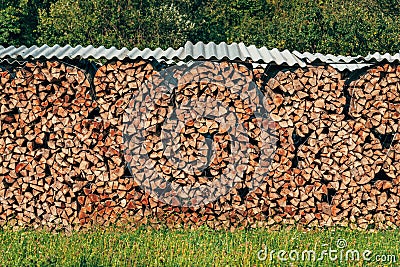 Large stack of chopped firewood on farmland drying in summer Stock Photo