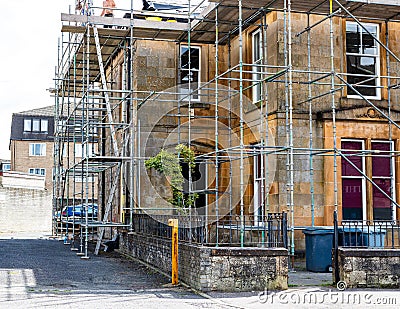 Large stone built fully scaffolded house or small business undergoing renovations Editorial Stock Photo