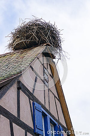 Large stork nest on the roof gable of a traditional wooden half-timbered house in the Alsace region of France Stock Photo