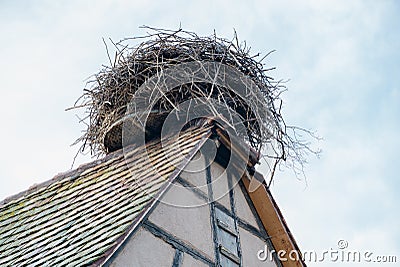 Large stork nest on the roof gable of a traditional wooden half-timbered house in the Alsace region of France Stock Photo