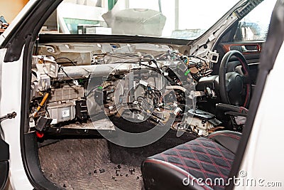 A large tangle of ravel multicolored wires from the car wiring lies in the cabin of dismantled car with connectors and plugs, a Stock Photo