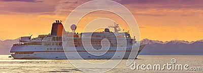 Large tourist cruise ship in the Pacific Ocean bay at sunset Stock Photo
