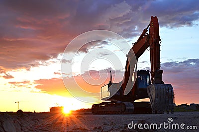 Large tracked excavator on a construction site against the background of the awesome sunset. Stock Photo