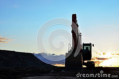 Large tracked excavator on a construction site against the background of the awesome sunset Stock Photo