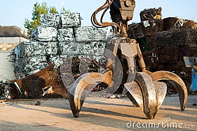 Large tracked excavator working a steel pile at a metal recycle yard. Industrial scrap metal recycling Stock Photo