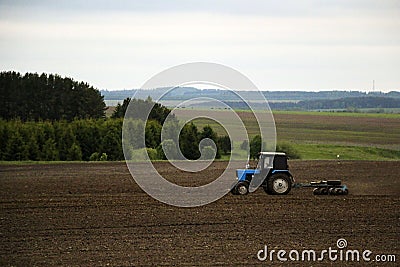 Large tractor with plow plows field before spring sowing of crops. tractor with harrow drives across plowed field and levels Stock Photo