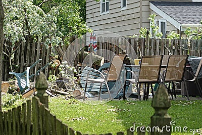 A large tree trunk is seen protruding through a broken wooden fence after a wind storm caused the tree to fall on it Stock Photo