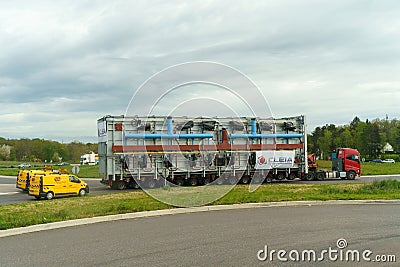 A large truck is driving along the highway, accompanied by special vehicles. Editorial Stock Photo