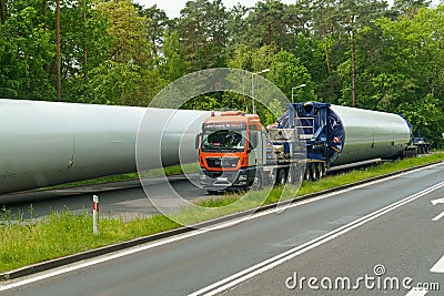 A large truck is driving along the highway, carrying a cylindrical load. Editorial Stock Photo