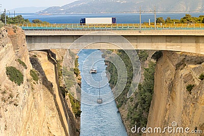 Large truck traversing the bridge of isthmus of Corinth in Greece while the boats are travelling in the bottom. Stock Photo