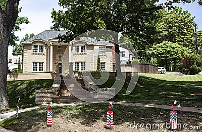 Large upscale brick house in leafy neighborhood with firecracker 4th of July ornaments in front Stock Photo