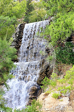 Large waterfall with radon water among the boulders at the foot of the mountain in Loutraki, Greece, vertical image Stock Photo