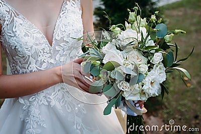 A large wedding bouquet in the hands of a beautiful bride of white and milk roses Stock Photo