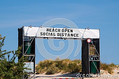 Large white banner over entrance to a beach that says, Beach Open Social Distance Stock Photo