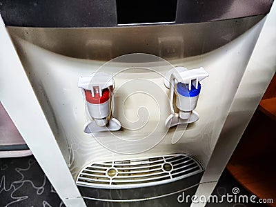 Large white water cooler with two taps. A soft serve machine with red and blue levers Stock Photo