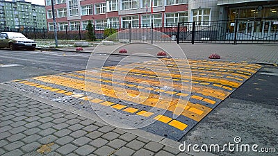 Large wide caution speed bump near apartment building and school. Sleeping policeman. Road safety regulations. Traffic rules conce Editorial Stock Photo