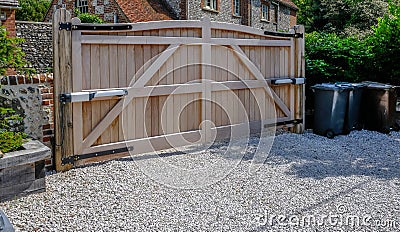 Large wooden entry electric gates with stone driveway Stock Photo