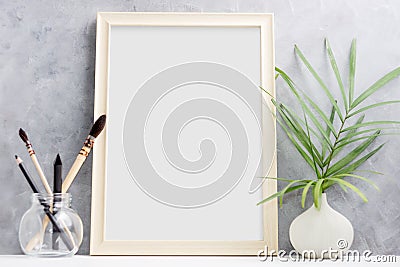 Large wooden Photo frame mock up with green palm leaves in vase and brushes in glass on shelf. Scandinavian style Stock Photo