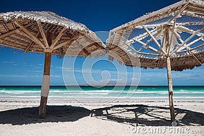 Large wooden umbrellas at sandy tropical beach Stock Photo