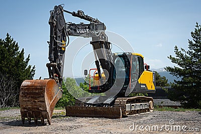 Large yellow and black Volvo EC160E excavator with a bucket in a construction site with trees Editorial Stock Photo