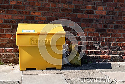 Large yellow grit salt container on pavement sidewalk Stock Photo