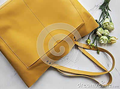 Large yellow leather bag and flowers Stock Photo