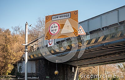 Large yellow Low Bridge sign on a railway bridge, warning of height restriction Editorial Stock Photo